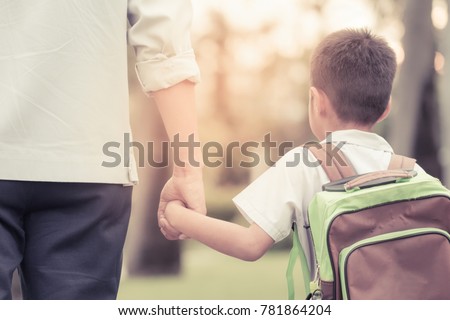 Father and son hold hands together are walking in the garden at evening with vintage color tone
