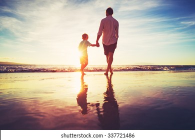 Father and Son Holding Hands Walking Together on the Beach at Sunset