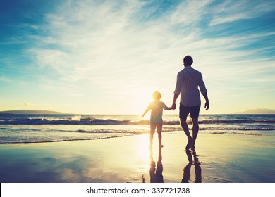Father and Son Holding Hands Walking Together on the Beach at Sunset