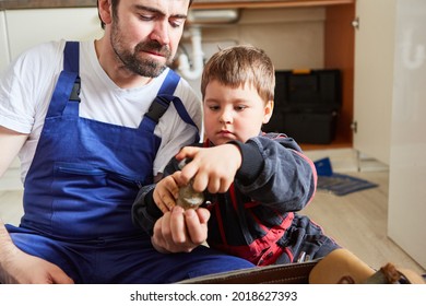 Father And Son As Home Improvement Team In The Kitchen Hold A Broken Shut-off Valve