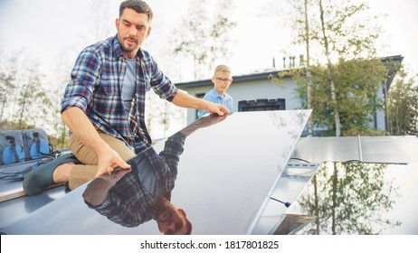 Father And Son Installing Solar Panels To A Metal Basis With A Drill. They Work On A House Roof On A Sunny Day. Concept Of Ecological Renewable Energy At Home And Quality Family Time.