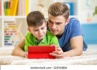 father and son kid playing with tablet computer at home