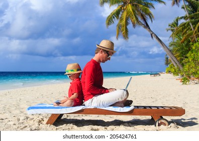 Father And Son With Laptop On Beach Vacation