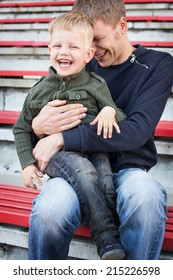 Father And Son Laughing In Empty Stadium. Portrait