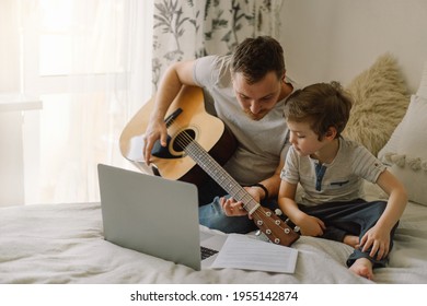 Father And Son Learn To Play The Acoustic Guitar In An Online Lesson. Free Time To Spend With My Son At Home, Teaching Him To Play The Guitar. Happy Father's Day