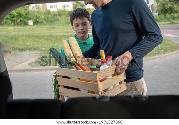 Father and son load purchases\
into trunk of car. Concept of eco-friendly materials. Close-up\
photo.