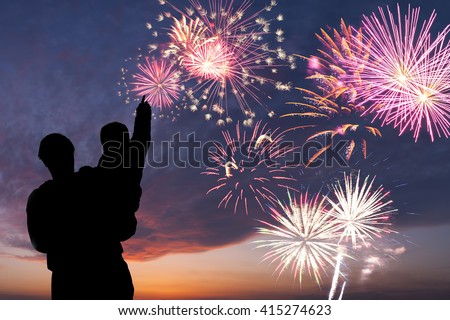 Father and son look at holiday firework in sky, happy family