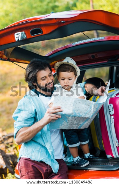 father and son\
looking at map at car\
trunk