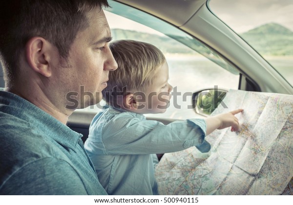 Father and son looking on\
map in car
