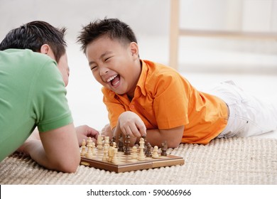 Father And Son Lying On Floor, Playing Chess, Laughing