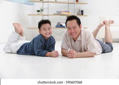 Father And Son Lying On Floor, Smiling At Camera, Portrait