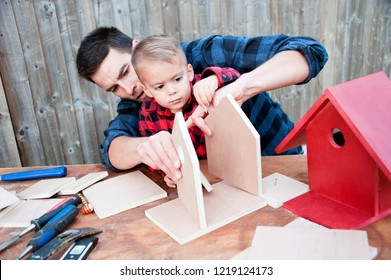 Father And Son Making A Birdhouse. Dad And Son Focus On Building The Perfect Birdhouse For Their Bird Visitors. 