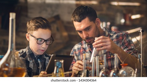 Father And Son Are Making Chemistry Experiments While Checking A Tablet Computer In A Garage At Home.