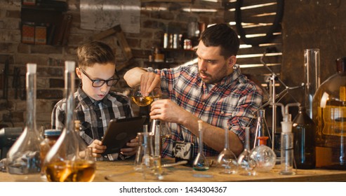 Father And Son Are Making Chemistry Experiments While Checking A Tablet Computer In A Garage At Home.