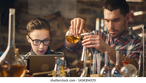 Father And Son Are Making Chemistry Experiments While Checking A Tablet Computer In A Garage At Home.