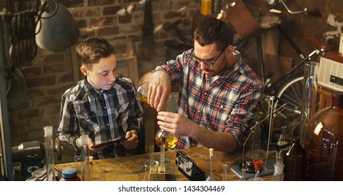 Father And Son Are Making Chemistry Experiments While Checking A Tablet Computer In A Garage At Home.