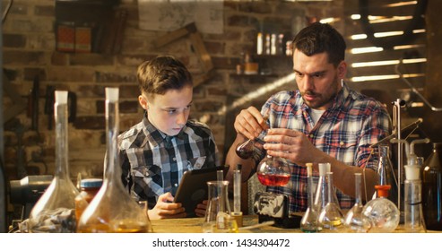 Father And Son Are Making Chemistry Experiments While Checking A Tablet Computer In A Garage At Home.