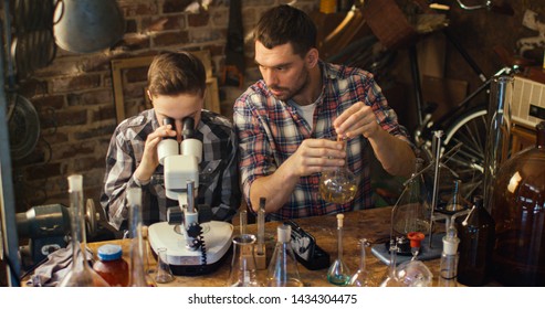 Father And Son Are Making Chemistry Experiments While Checking Microscope In A Garage At Home.