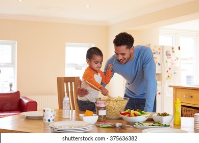 Father And Son Making Pasta Salad In Kitchen