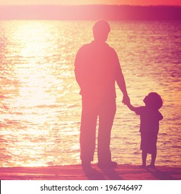 Father And Son  On A Dock At Sunset, Boy Looking Up At His Father.