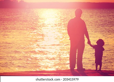 Father and son  on a dock at sunset, boy looking up at his father