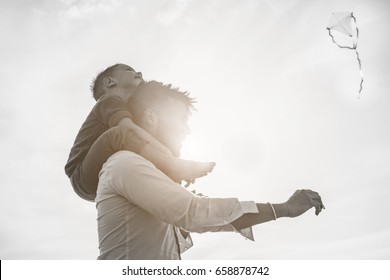 Father With Son On Shoulder Flying With Kite And Having Fun On The Beach - Dad Enjoying Time With His Child - Love, Freedom And Family Concept - Soft Focus On Kid Face - Black And White Editing