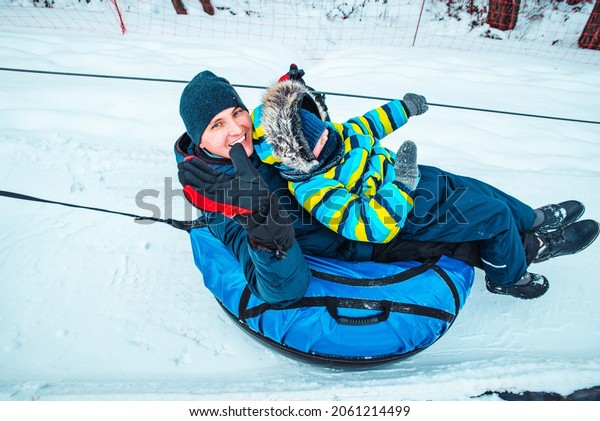 father with son on snow tube. pull up to hill.\
winter time