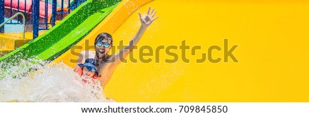 Father and son on a water slide in the water park. Long Format.