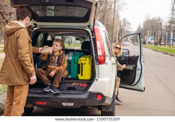 father with son packing bags to car trunk. car\
travel concept. adventure\
time