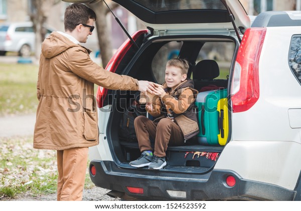 father with son packing bags to car trunk. car\
travel concept