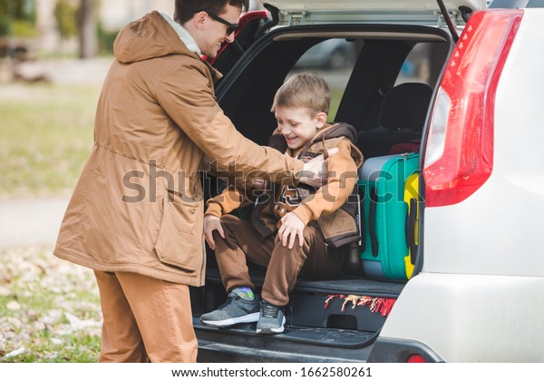 father with son packing bags to car trunk. car\
travel concept