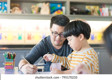 Father and son are painting together in the study room.