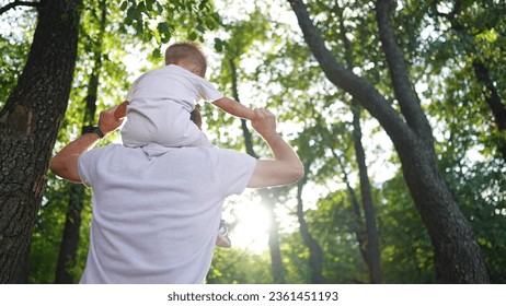 father and son in the park. dad carries his son on his neck through the forest park glare of the sun outdoor recreation with children. happy family kid dream concept. father son piggyback lifestyle - Powered by Shutterstock