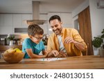 Father and son play board game have fun together at home