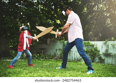 Father, son and play fighting with sword for bonding or VR in costume, cosplay or backyard at home. Fun dad, child or little boy enjoying outdoor game on grass field, lawn or virtual reality at house - Powered by Shutterstock