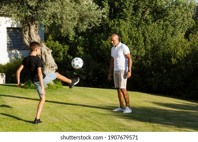 Father And Son Play Soccer In The Lawn Of The Home Garden