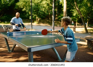 Father and son play table tennis outdoors
