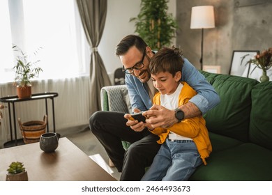 Father and son play video games on a mobile phone and enjoy at home - Powered by Shutterstock