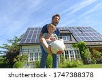 Father and son playing with ball in garden of solar paneled house