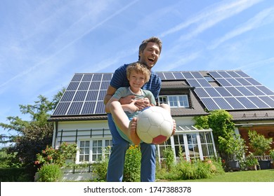 Father and son playing with ball in garden of solar paneled house - Shutterstock ID 1747388378