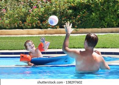 Father and son playing ball in a swimming pool