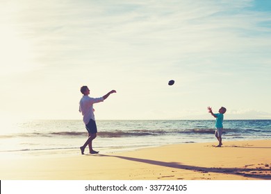 Father And Son Playing Catch Throwing Football On The Beach At Sunset