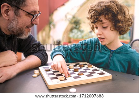 Father and son playing checkers in the courtyard during quarantine period of coronavirus lockdown., life