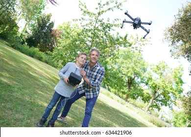 Father and son playing with flying drone in garden - Powered by Shutterstock