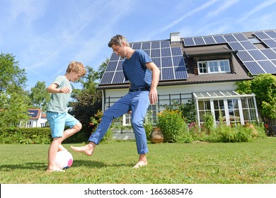 Father and son playing football in garden of solar paneled house - Shutterstock ID 1663685476