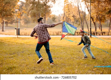 Father and son playing with a kite in an autumn park - Powered by Shutterstock