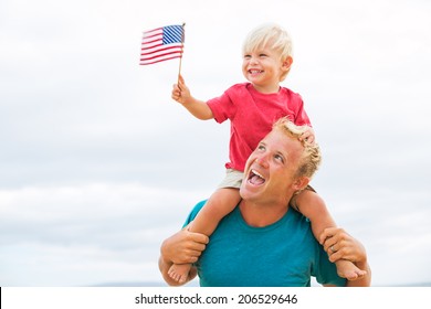 Father and son playing on the beach with American flag. USA celebrate 4th of July. - Powered by Shutterstock