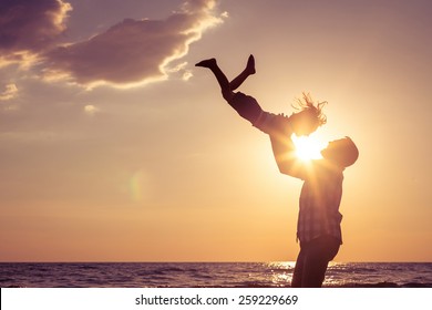 Father and son playing on the beach at the sunset time. Concept of friendly family. - Powered by Shutterstock