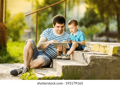 Father And Son Playing On Digital Tablet Outside