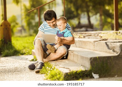 Father And Son Playing On Digital Tablet Outside